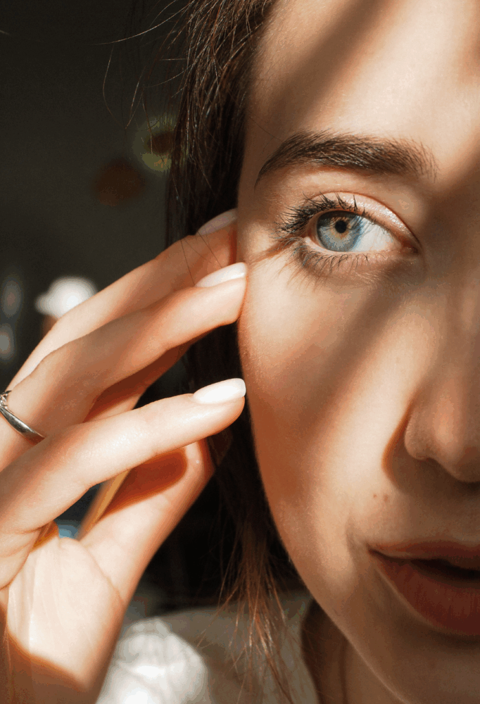 Nahaufahme von einer jungen Frau, die halb im BIld ist und nach Links schaut. Sie wird beleuchtet vom natürlichen Licht und hat volle Augenbrauen