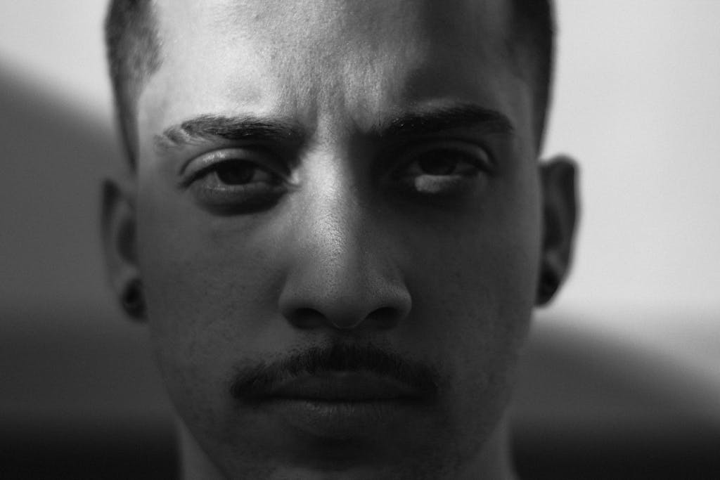 A striking black and white close-up portrait of a young man with a serious expression.