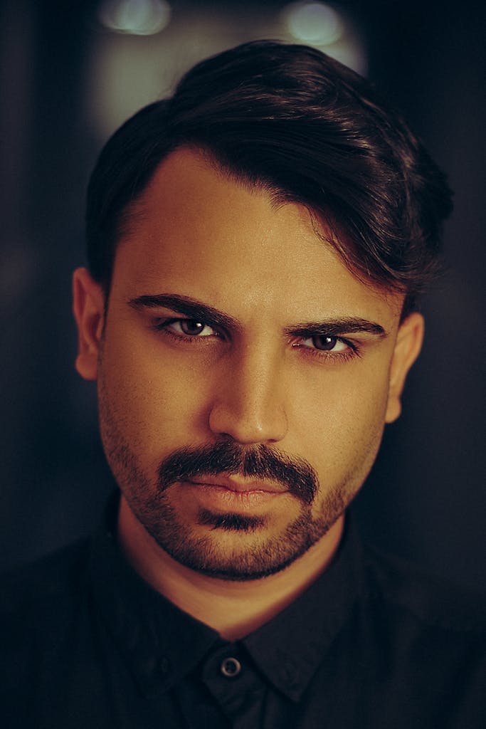 Intense portrait of a man with beard and mustache, creating a dramatic mood.