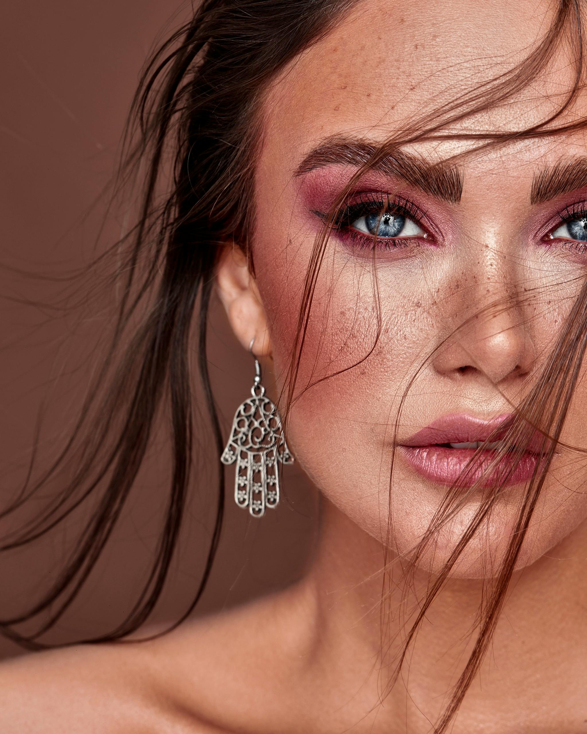 Close-up portrait of a woman with striking makeup and dangling earring.